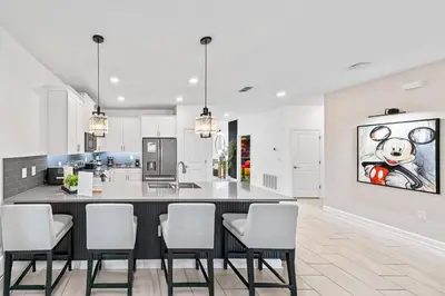 a kitchen with a bar with chairs and a painting on the wall at 2869 Epic Themed Mega Home at Storey Lake 7DB in Kissimmee