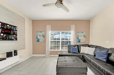 a living room with a leather couch and a window at Heated pool Lazy River Mini Golf Near Disney Resort in Kissimmee