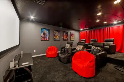 a cinema room with red chairs and a screen at The Ultimate Mansion on Solara Resort Orlando Mansion 5304 in Kissimmee