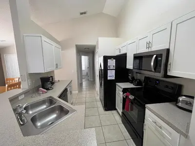 a kitchen with a stainless steel sink and white cabinets at Beautiful 4 Bed In Prime Location in Kissimmee