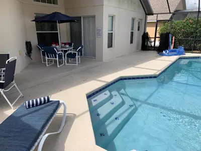 a swimming pool with a table and an umbrella at Beautiful 4 Bed In Prime Location in Kissimmee
