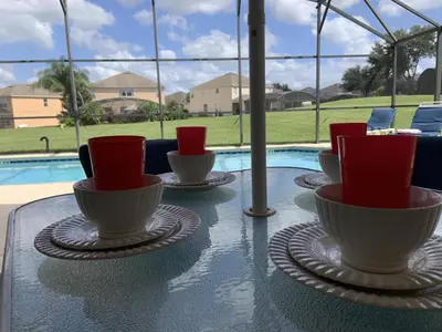a table with bowls and cups on it with a pool at Beautiful 4 Bed In Prime Location in Kissimmee