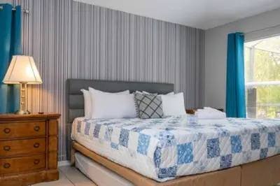 a bedroom with a bed with blue curtains and a window at Amazing 5 BR wgame room minutes from Disney in Kissimmee