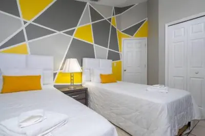 two beds in a bedroom with yellow and gray walls at Amazing 5 BR wgame room minutes from Disney in Kissimmee