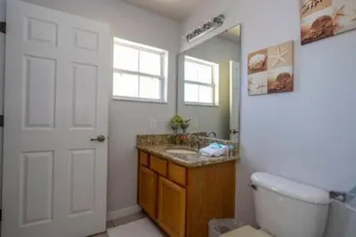 a bathroom with a sink and a toilet and a mirror at Cozy 3 BR wprivate pool in Kissimmee