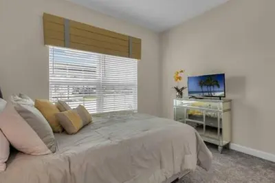 a bedroom with a bed with a window and a television at Storey Lake Resort 5BD Private Pool Close to Disne in Kissimmee