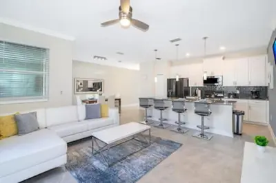 a living room with a white couch and a kitchen at Gorgeous Storey Lake 4BR in Kissimmee