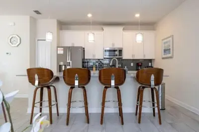 a kitchen with wooden bar stools and a counter at Gorgeous Home with pool and lake view in Kissimmee