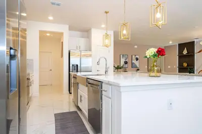 a kitchen with white cabinets and a counter with flowers in a vase at Stunning 15 suites close to Disney in Kissimmee
