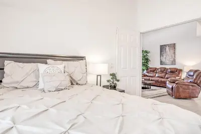 a white bedroom with a large bed and leather chairs at Private Pool Home Near Disney & Universal Studios in Kissimmee