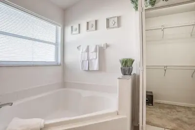 a white bathroom with a tub and a shower at Private Pool Home Near Disney & Universal Studios in Kissimmee