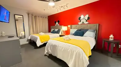 a bedroom with two beds and a red wall at Whimsical Condo 1.5M from Disney in Orlando