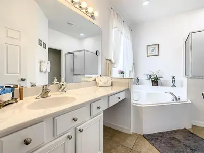 a white bathroom with a tub and a sink and a bath tub at 7BR Villa in Emerald Island w/ Resort Perks in Kissimmee
