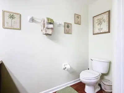 a bathroom with a toilet and some pictures on the wall at Adventureland Oasis - Resort Near Disney in Kissimmee