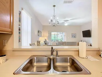 a kitchen with a sink and a living room at Family Getaway: 4BR Townhome by Old Town in Orlando