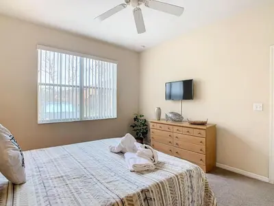 a bedroom with a bed with a dresser and a tv at Family Getaway: 4BR Townhome by Old Town in Orlando