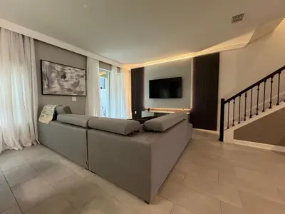 a living room with a couch and a flat screen tv at 5BR c/Piscina Privada | Luxo em Storey Lake in Kissimmee