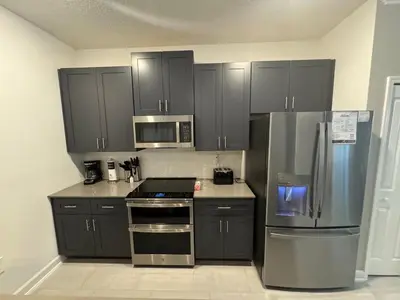 a kitchen with black cabinets and a stainless steel refrigerator at 5BR c/Piscina Privada | Luxo em Storey Lake in Kissimmee