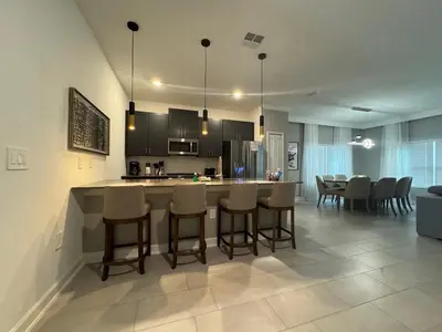 a kitchen and dining room with a bar and chairs at 5BR c/Piscina Privada | Luxo em Storey Lake in Kissimmee