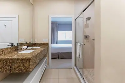 a bathroom with two sinks and a shower and a bed at 7639- Encantadora Casa com 3 Suítes no Magic Village Yards, Perto da Disney e da Rota 192 in Orlando