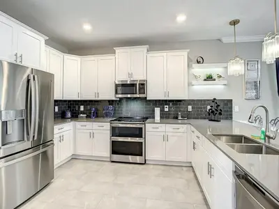 a kitchen with white cabinets and stainless steel appliances at Magical Mansion - 15 Min to Disney - Storey Lake in Kissimmee