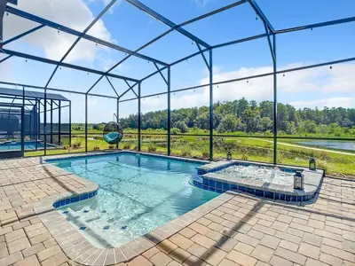 a large swimming pool in a glass house with a view at Magical Mansion - 15 Min to Disney - Storey Lake in Kissimmee