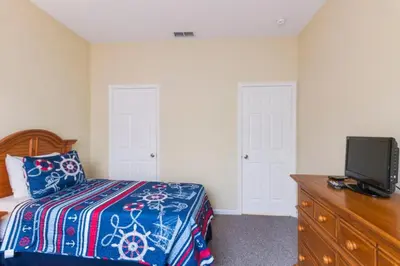 a bedroom with a bed and a dresser with a tv at Aruba Palms Villa Near Disney & Attractions in Kissimmee
