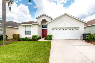 a white house with a red garage at Aruba Palms Villa Near Disney & Attractions in Kissimmee