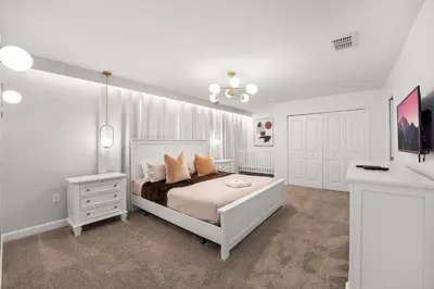 a white bedroom with a bed and a chandelier at 2858 Storey Lake brand new 19guests pool game room in Kissimmee