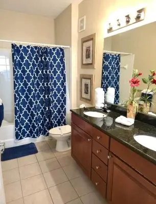 a bathroom with two sinks and a blue shower curtain at Cane Island Resort 2BR Condo, Close to Attractions in Kissimmee