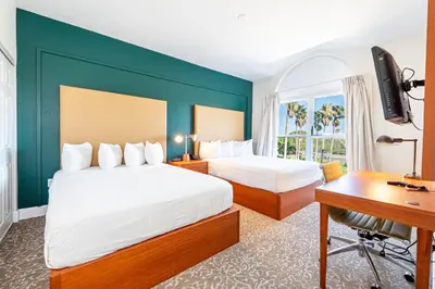a hotel room with two beds and a desk at Montreal Suites Orlando in Orlando