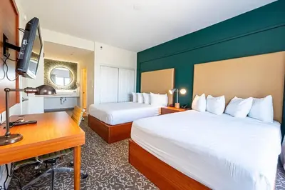 a hotel room with two beds and a desk at Montreal Suites Orlando in Orlando
