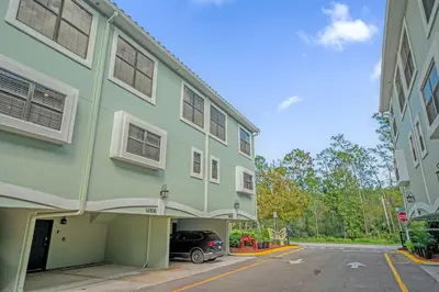 a green building with a car parked in a parking lot at Summer Fun Starts Here - Townhome by Disney! in Orlando