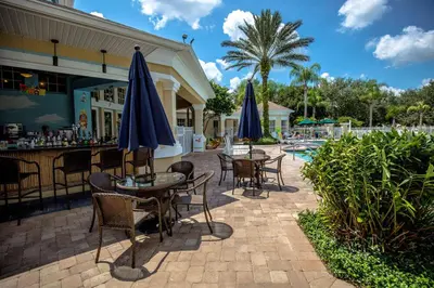 a patio with tables and chairs with umbrellas next to a pool at Great place to stay close to Disney Parks in Kissimmee