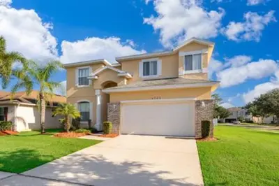 a large house with a garage in a yard at Ruby Reds Escape in Kissimmee