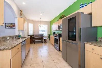 a large kitchen with green walls and a table at Ruby Reds Escape in Kissimmee