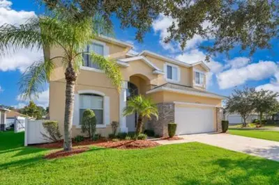 a large house with a palm tree in front of it at Ruby Reds Escape in Kissimmee