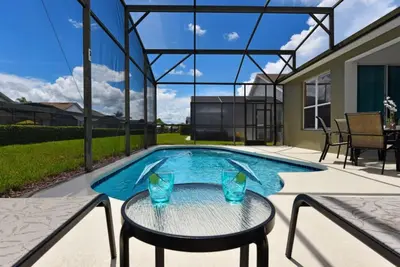 a patio with a table and a swimming pool at Caribbean Breeze: Pool Home 3 Miles to Disney in Kissimmee