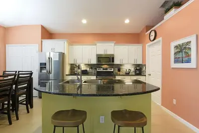 a kitchen with a large island with bar stools at Caribbean Breeze: Pool Home 3 Miles to Disney in Kissimmee