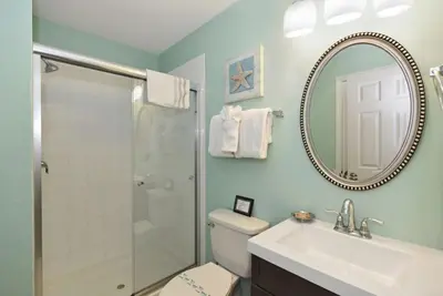 a bathroom with a toilet and a sink and a mirror at Caribbean Breeze: Pool Home 3 Miles to Disney in Kissimmee