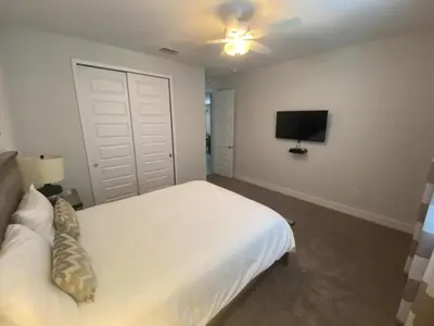 a bedroom with a white bed and a flat screen tv at Elegant Family Home | Pool, Spa & Themed Rooms in Orlando