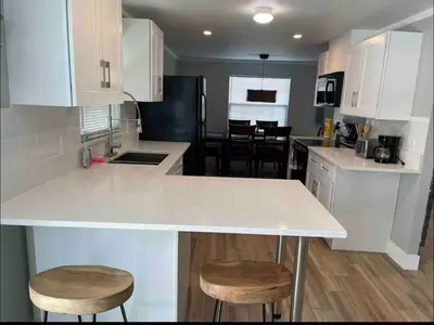 a kitchen with a white counter and stools in it at Agradable casa parqueos gratis in Orlando