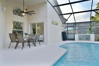 a patio with a table and chairs next to a swimming pool at Four Seasons Vacation, heated Pool, 3mile 2 Disney in Kissimmee