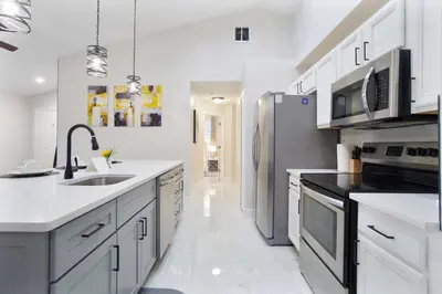 a kitchen with white cabinets and a stainless steel refrigerator at Four Seasons Vacation, heated Pool, 3mile 2 Disney in Kissimmee
