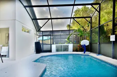 a swimming pool in a house with a large window at Four Seasons Vacation, heated Pool, 3mile 2 Disney in Kissimmee