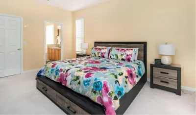 a bedroom with a bed with a colorful comforter at Emerald Island Getaway – Sleeps 13! in Kissimmee