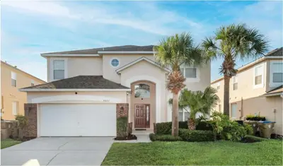 a house with palm trees in front of it at Emerald Island Getaway – Sleeps 13! in Kissimmee