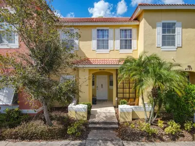 a yellow house with palm trees in front of it at Hogwarts Escape: Magical Retreat Near Disney in Kissimmee