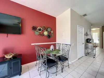 a dining room with a table and a tv on a red wall at Krista's Tropical Escape: Resort Stay Near Disney in Kissimmee