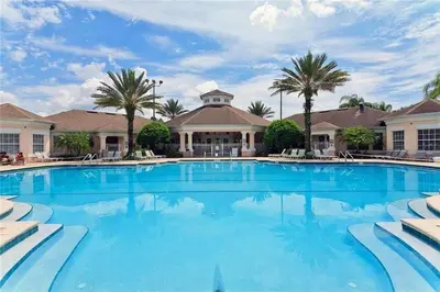a large swimming pool with palm trees and a building at Krista's Tropical Escape: Resort Stay Near Disney in Kissimmee
